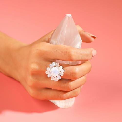 Hand holding a crystal with a large gemstone ring
