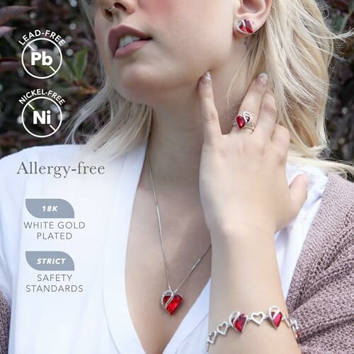 Woman wearing heart-shaped red jewelry set with allergy-free features.